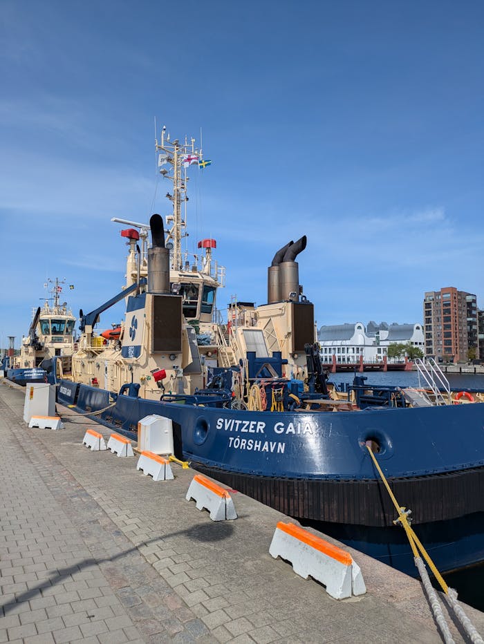 pexels-photo-32065295 Tugboats docked at a harbor under clear blue sky, showcasing maritime industry.